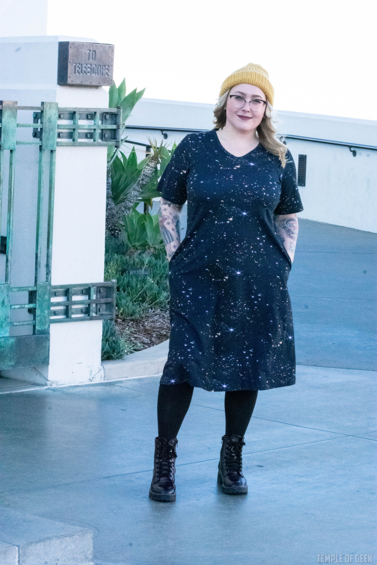 A model stands outside Griffith Observatory in a dress from Svaha and a yellow beanie.