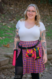 A woman models a gamer fashion utility belt with attachable character-themed pouches in the park. 