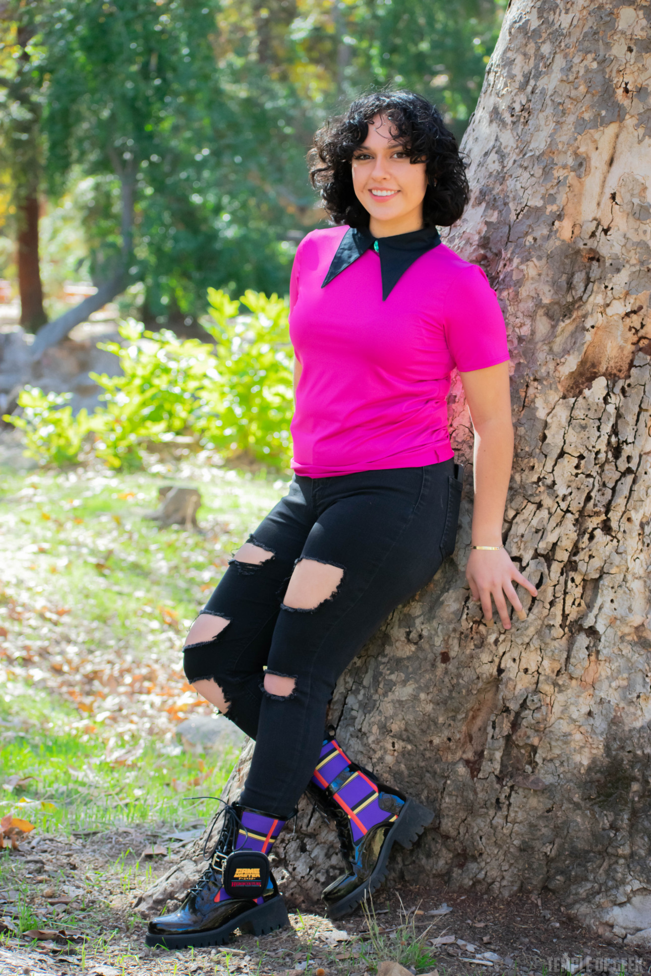 A model leans against a tree wearing gamer fashion and a pair of plaid boots.