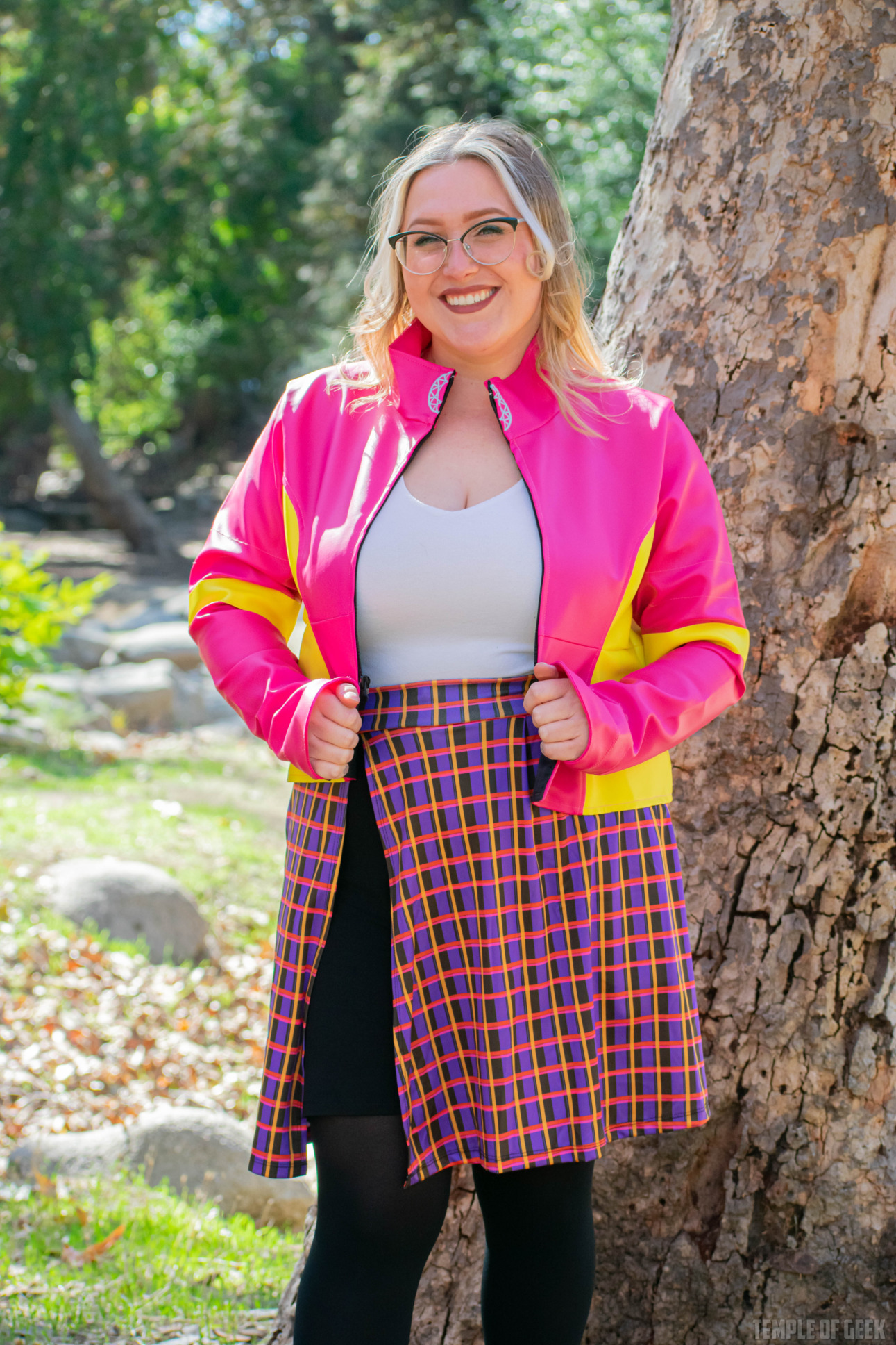 A model stands in front of a tree wearing a bright pink and yellow moto jacket from GameMaster + Heroicouture.