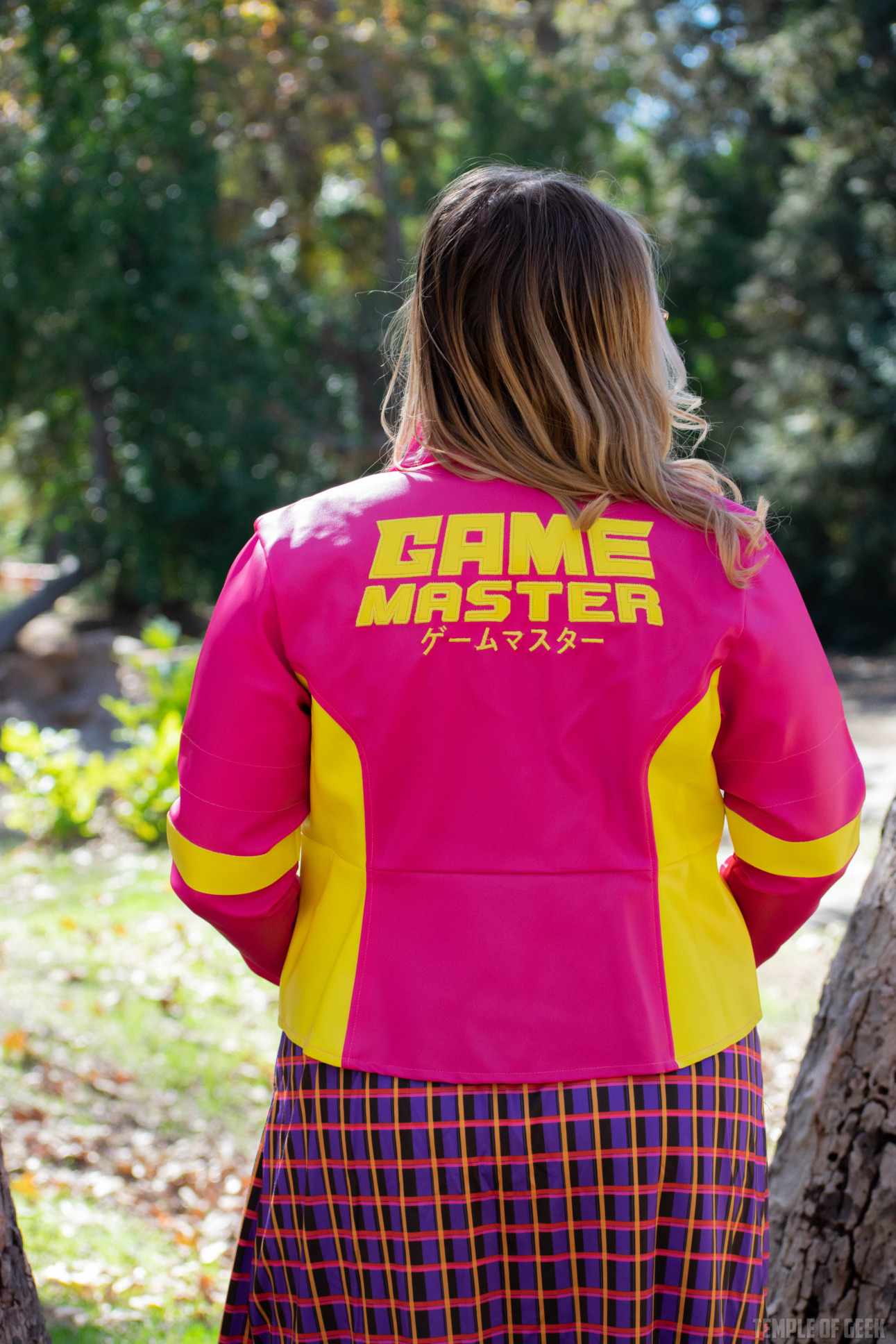 A closeup on the back of a pink and yellow moto jacket with the GameMaster logo embroidered across it.