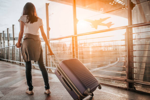 Young woman pulling suitcase in airport terminal. Use for convention travel.