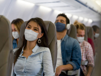 travelers on an airplane wearing masks - part of convention travel