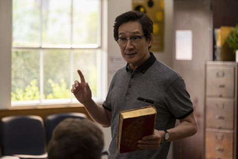 Ke Huy Quan standing with book in hand towards a group of students in a classroom - AMERICAN BORN CHINESE