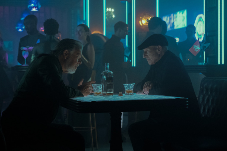 Jonathan Frakes as William Riker and Patrick Stewart as Jean-Luc Picard converse in a booth in a bar, Star Trek: Picard season 3. 