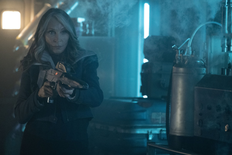 Gates McFadden as Dr. Beverly Crusher holds a phaser rifle to face an unknown threat in Star Trek: Picard season 3. 