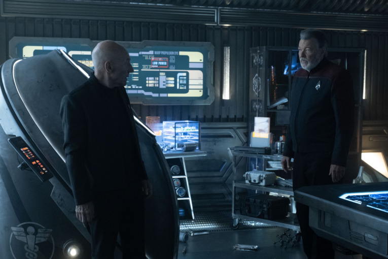 Patrick Stewart as Picard and Jonathan Frakes as Riker in Star Trek Picard standing face to face onboard the starship Eleos