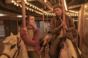 Ellie (Bella Ramsey) and Riley (Storm Reid) sit on horses on a carousel.