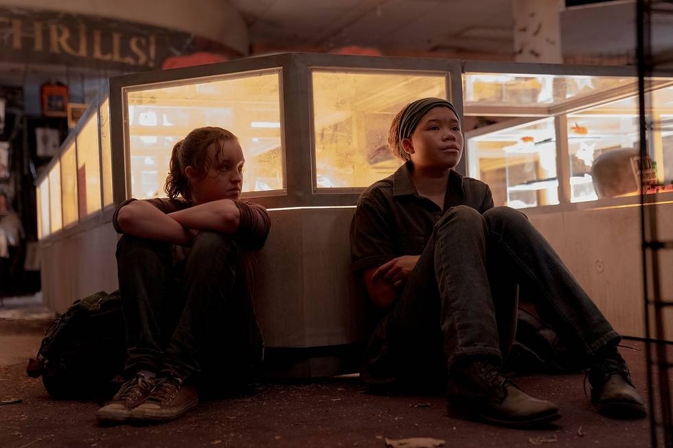 Ellie (Bella Ramsey) and Riley (Storm Reid) sit next to each other against a glass counter.