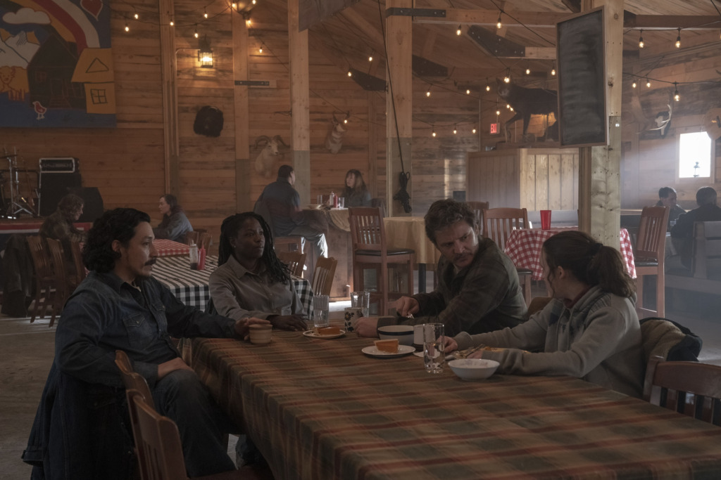 Tommy (Gabriel Luna), Maria (Rutina Wesley) sit across from Joel (Pedro Pascal) and Ellie (Bella Ramsey) in a dinning hall.