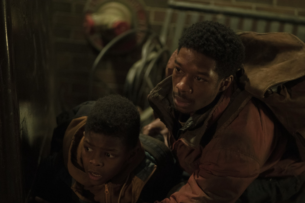 Keivonn Woodard as Sam and Lamar Johnson as Henry in The Last of Us look up at some threat.