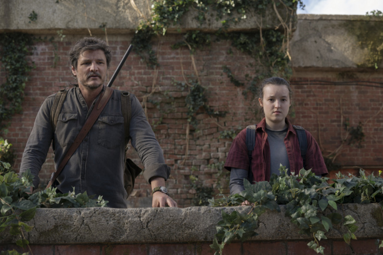 Joel (Pedro Pascal) stands next Ellie (Bella Ramsey) as they look out over a building.