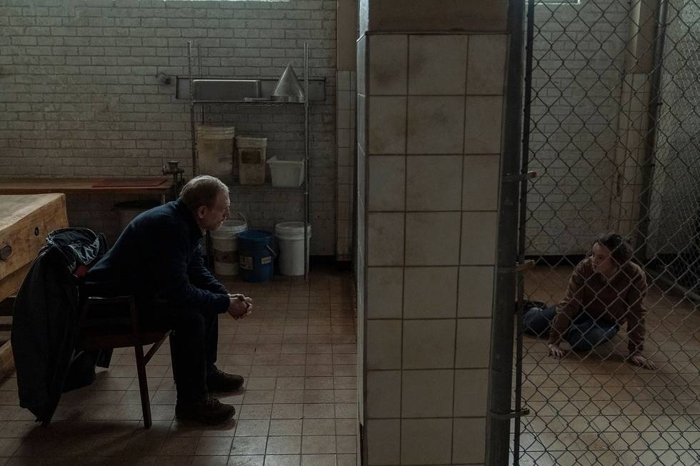 David (Scott Shepherd) sits outside of a cage where Ellie (Bella Ramsey) is being kept.