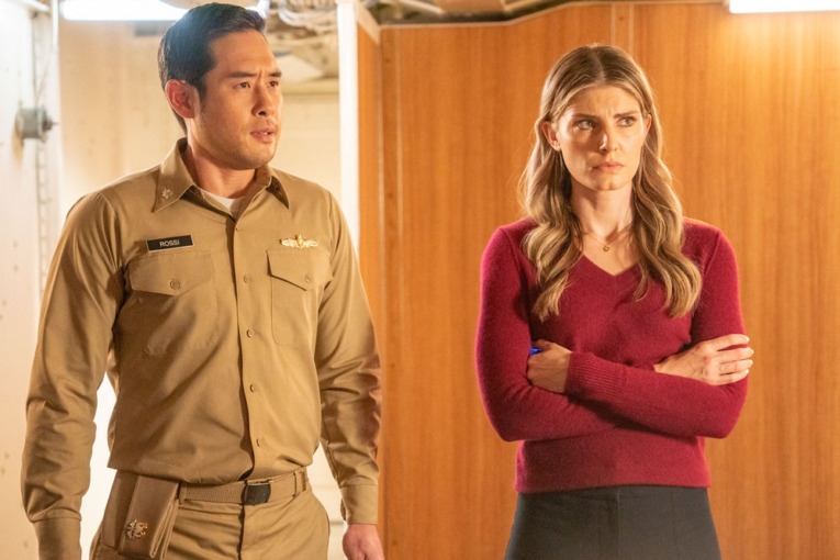 QUANTUM LEAP -- "SOS" Episode 114 -- Pictured: (l-r) Raymond Lee as Dr. Ben Song, Caitlin Bassett as Addison -- (Photo by: Ron Batzdorff/NBC). Ben is in an army uniform with his hands at his sides looking concerned. Addison stands next to home, arms crossed and looking stressed. 