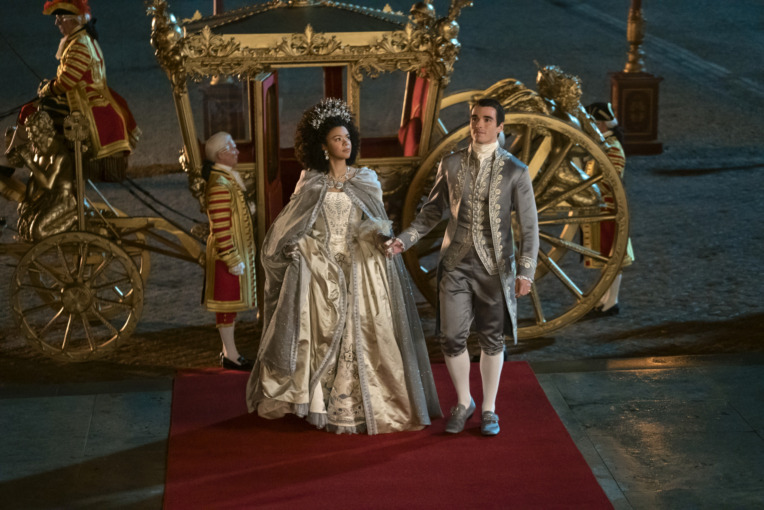 Queen Charlotte: A Bridgerton Story. (L to R) India Amarteifio as Young Queen Charlotte, Corey Mylchreest as Young King George in episode 1, stand outside of a golden carriage on their wedding day, about to enter their new home. 