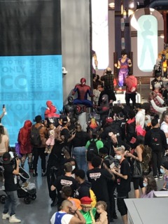 A trio of Spider-Man cosplayers pose for a large crowd at NYCC 2023