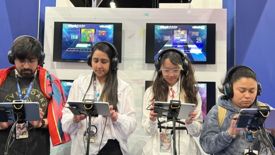 Attendees on a stage playing Hastune Miku on tablets at Anime Expo