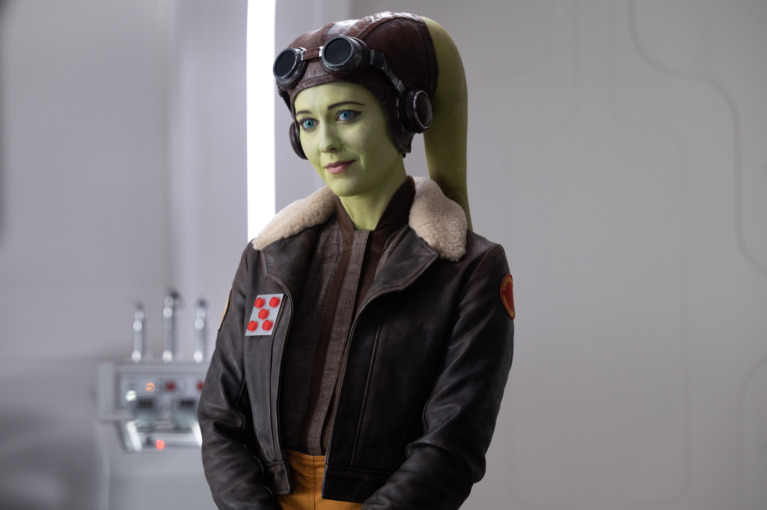 Hera Syndulla, a green Twi'lek wearing a dark brown pilot's cap and jacket.