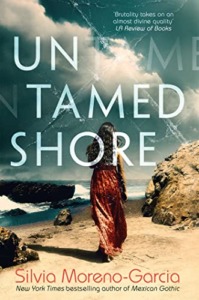 New cover for Silvia Moreno-Garcia's Untamed Shore. A woman walks along a beach. She is wearing a long skirt and is facing away from the reader.