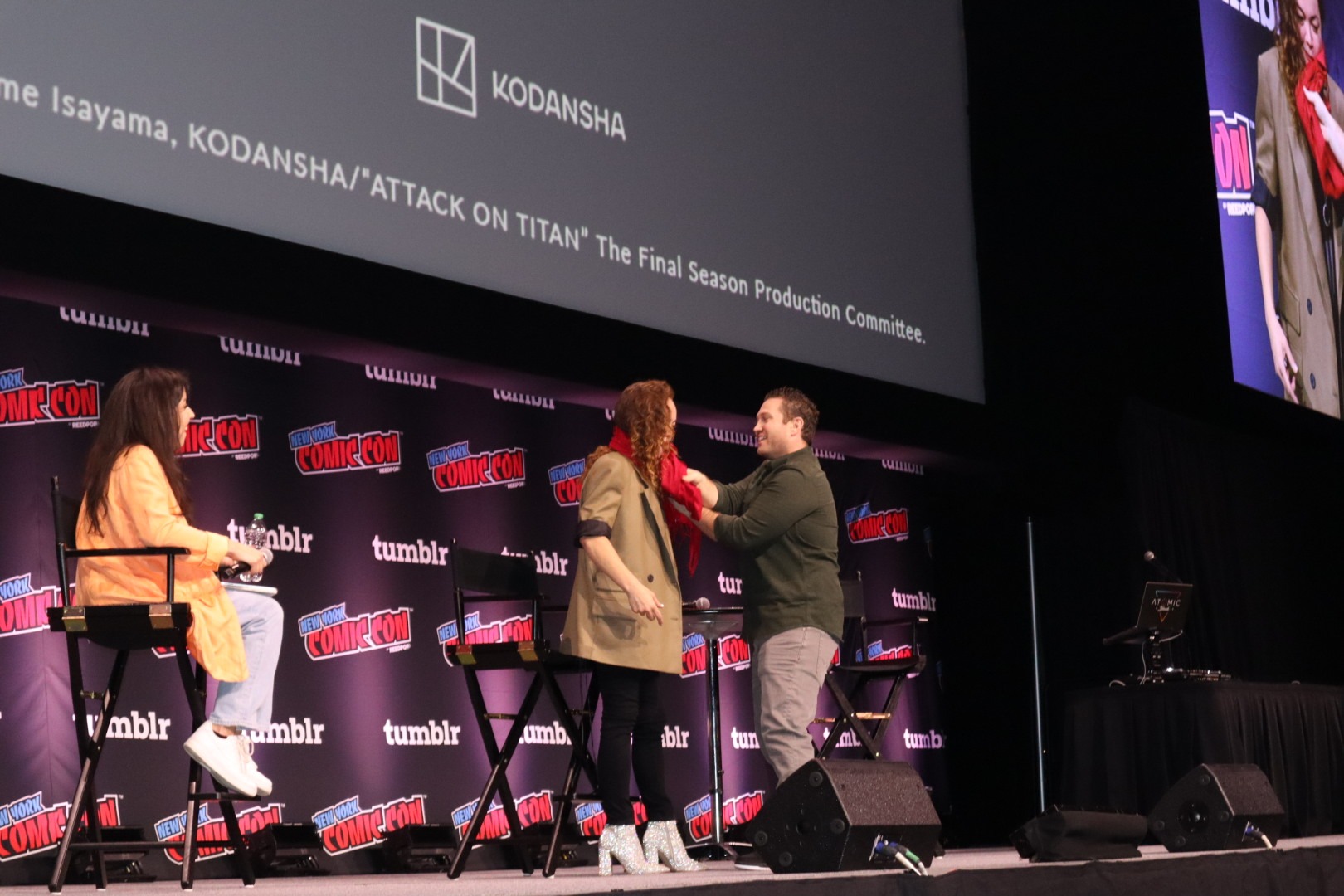 Bryce Papenbrook and Trina Nishimura embrace on stage for the Attack on Titan 10 Year Celebration and Dub panel at NYCC