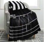 Picture of a black blanket that looks like movie clapboard draped over a grey arm chair