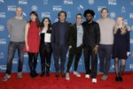 a group of men and women pose on a red carpet