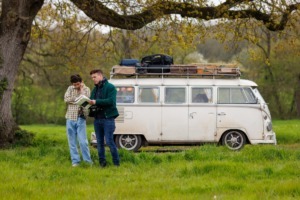 Picture of two men standing in a field in front of a van 