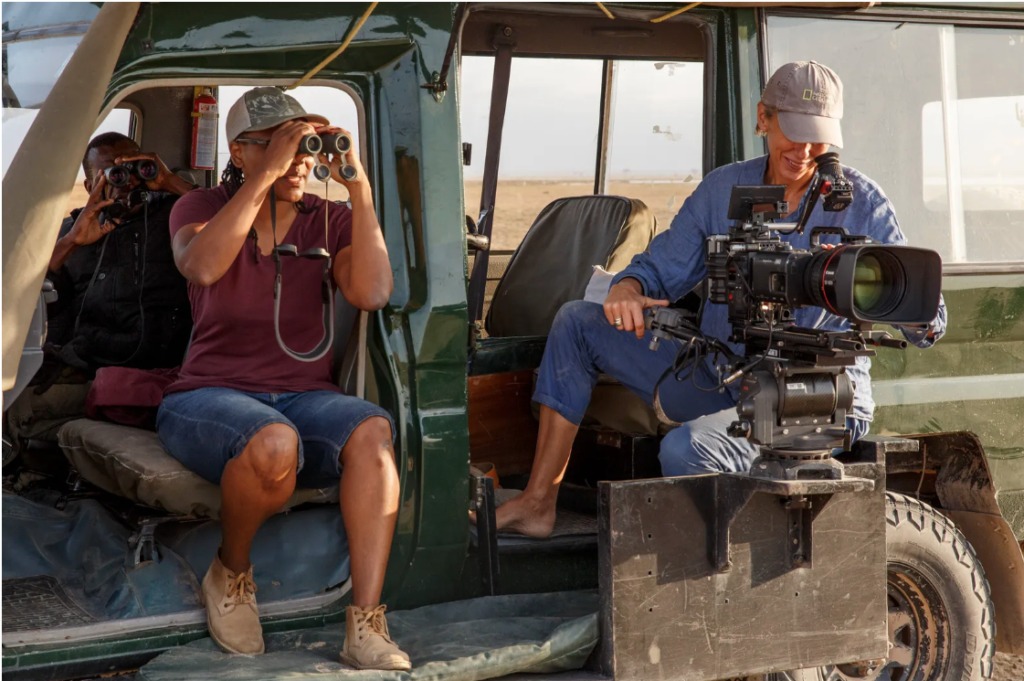 Faith Musembi and Sophie Darlington watch elephants from behind a camera.