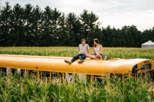 Picture of two people sitting on a bus in a cornfield