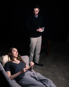 Picture of a woman lying on a sofa and a man standing over her. 