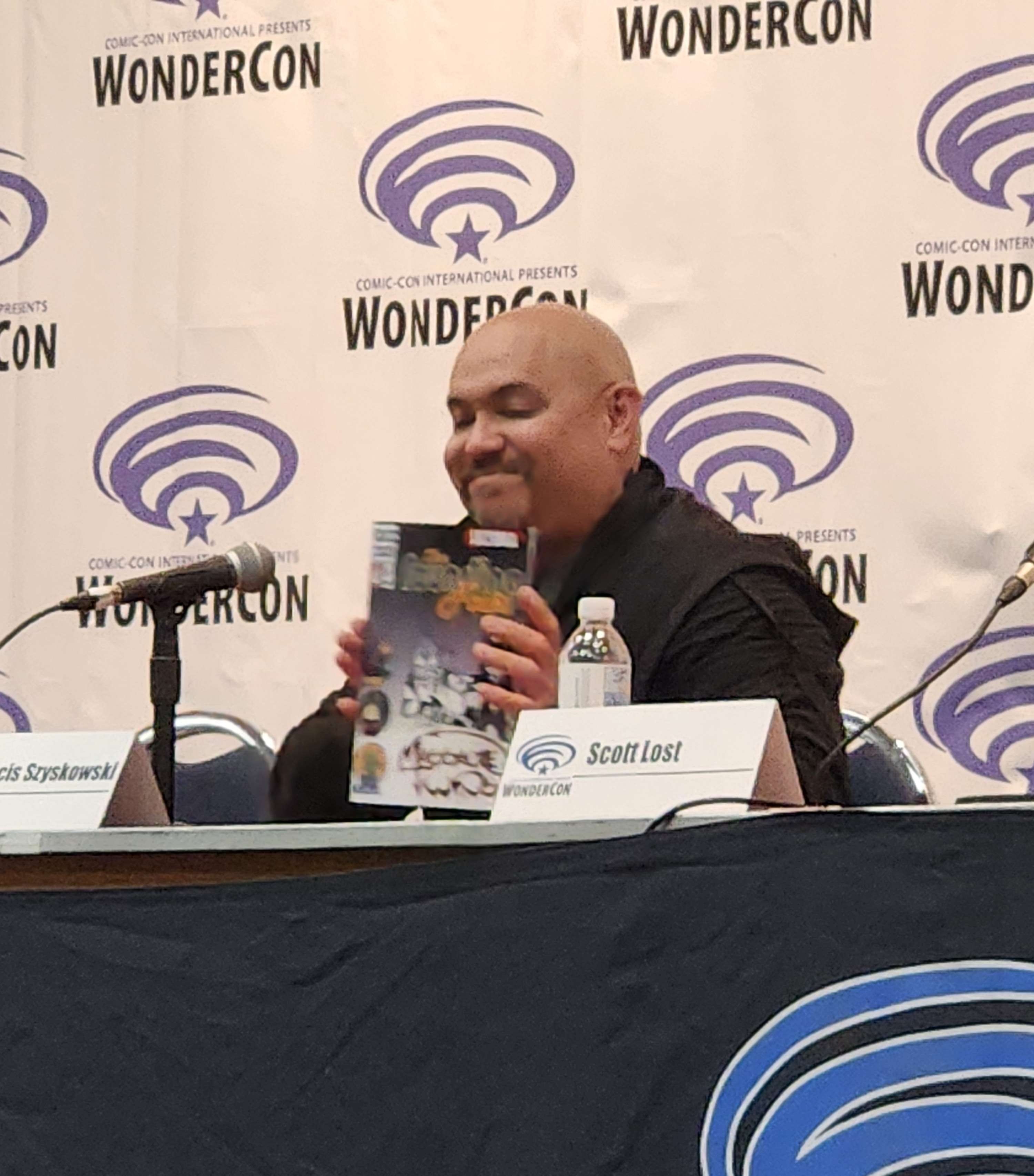 Francis Sky sitting at the panel of "The Relationship between Comics and Pro Wrestling" holding his preview issue of "The Massacre Twins"