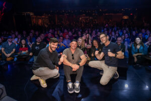 picture of three men on stage in front of a crowd