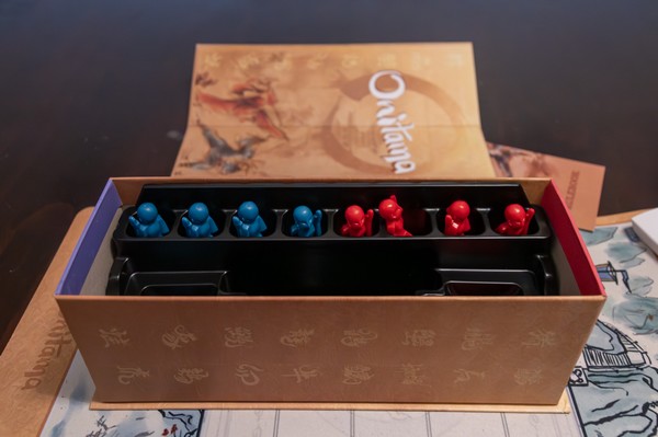 Onitama Board game red and blue pawns in the box.