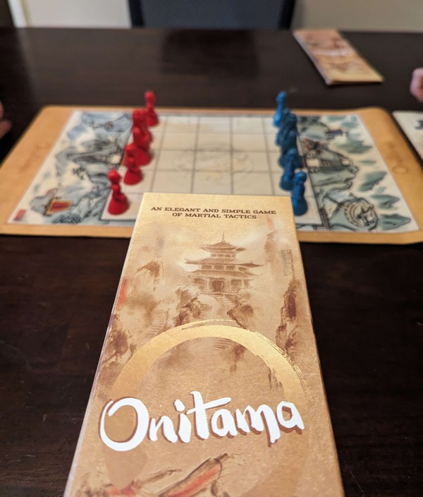 Onitama Board Game set up with blue and red pawns in respectable places.