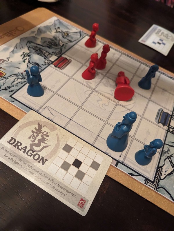 Onitama board game at play with red pawns dominating blue pawns, demonstrating game Move cards