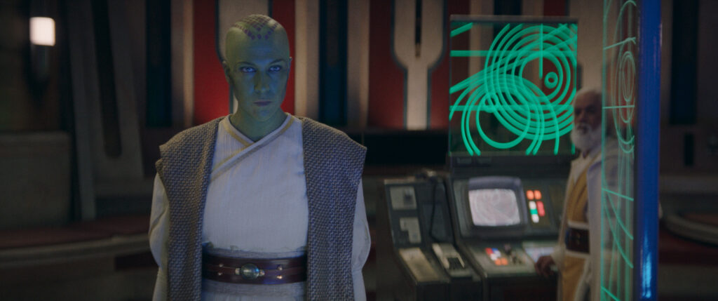 Green Mirialan Jedi Master Vernestra Rwoh stands before a small council