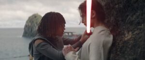 Another perspective of Osha pinning The Stranger against a cliffside. The red lightsaber is between them, and his hand rests on her forearm.