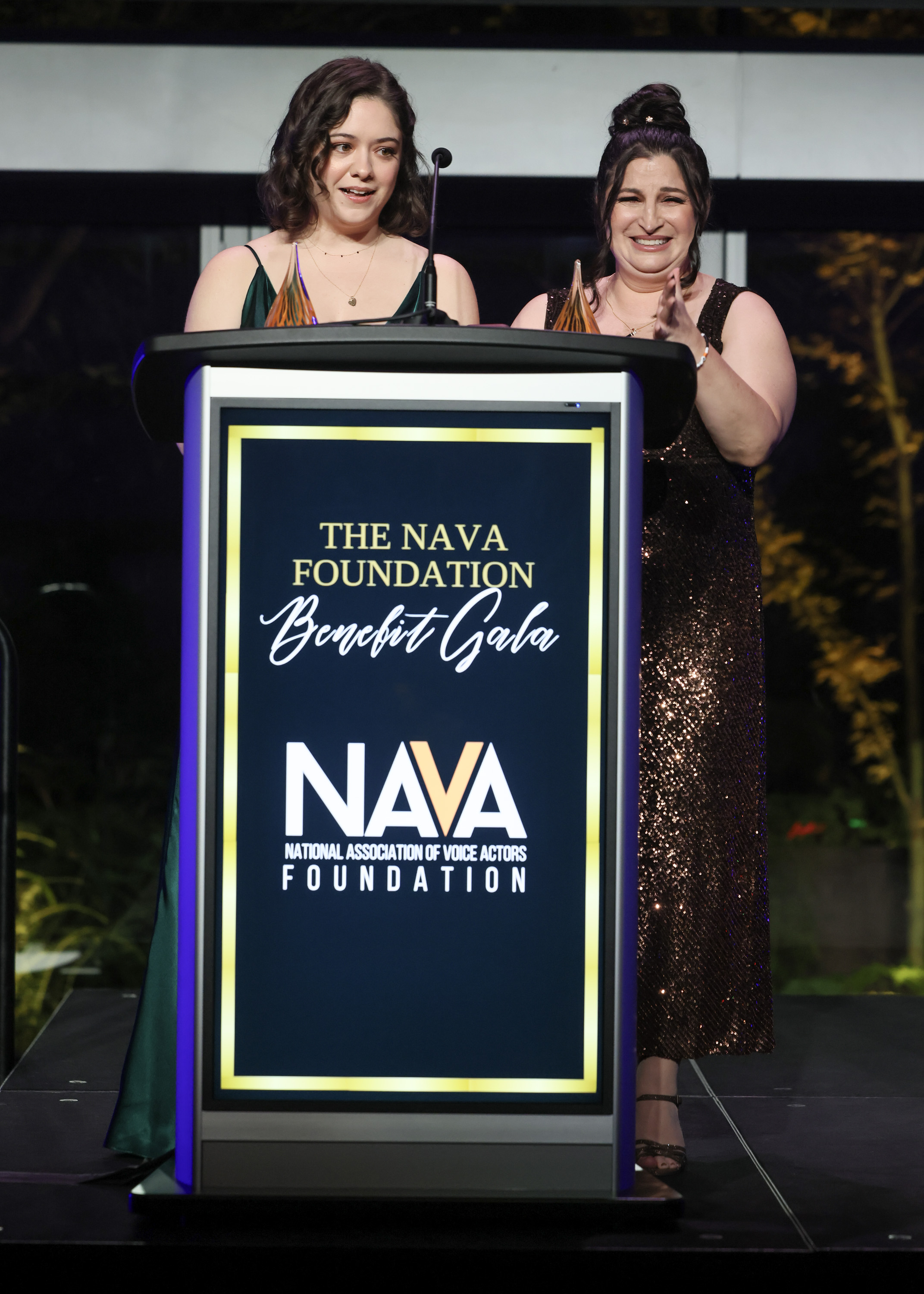 two women accept an award on a stage 