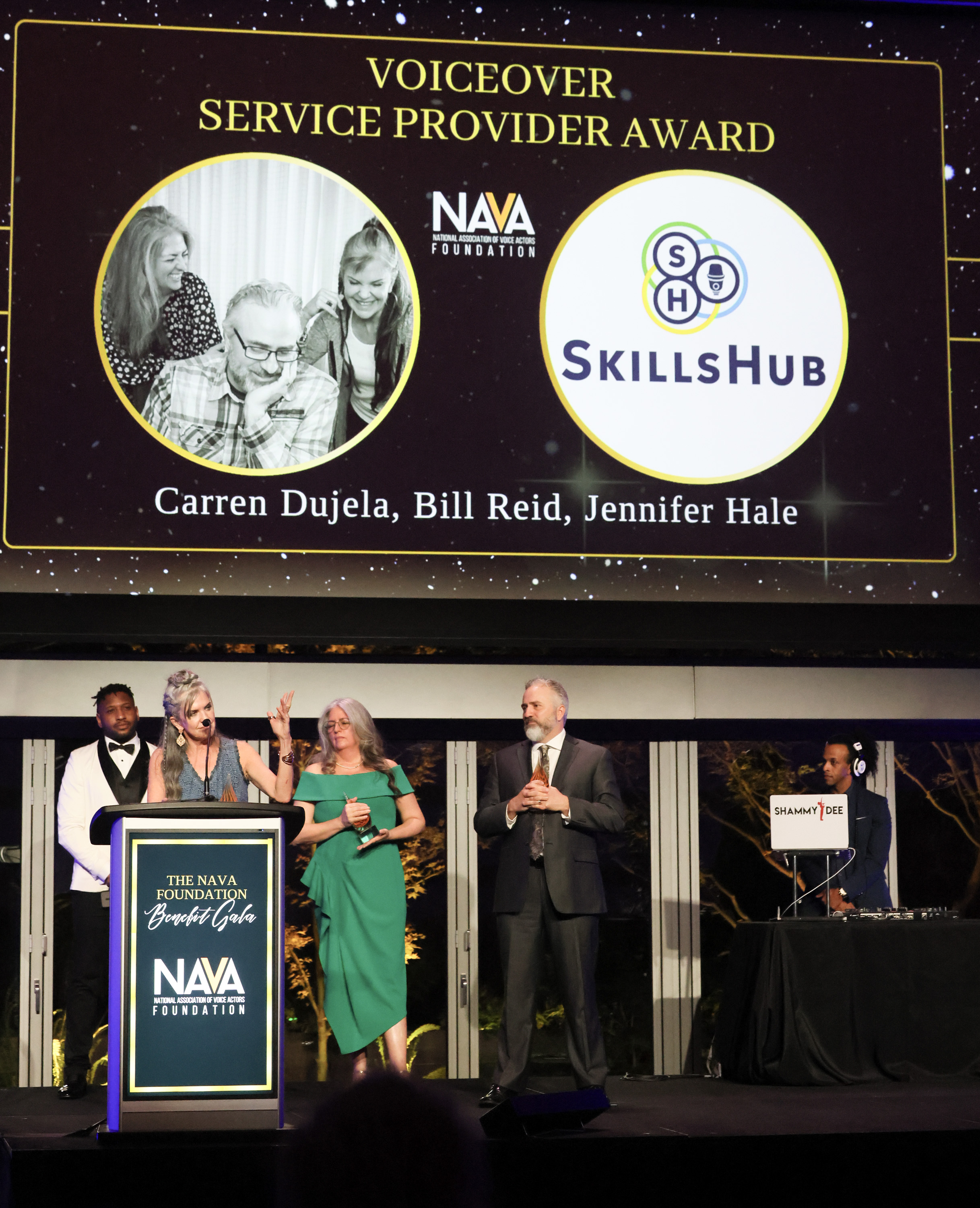 two women and a man accept an award on a stage