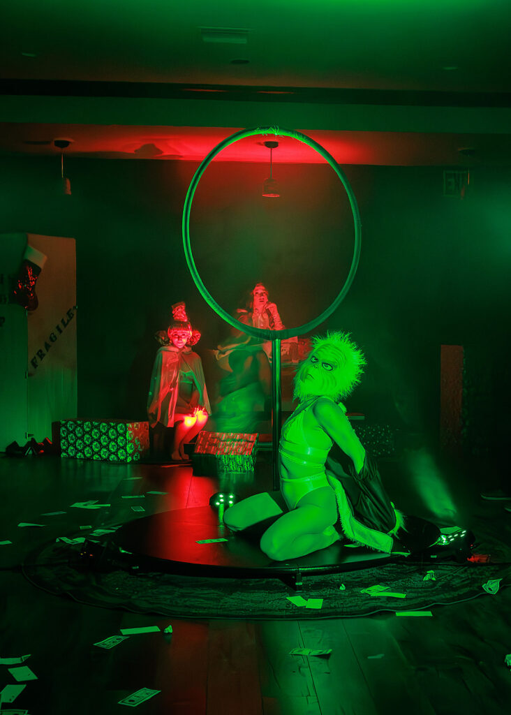 woman dressed as the grinch kneeling in front of lolllipop hoop 