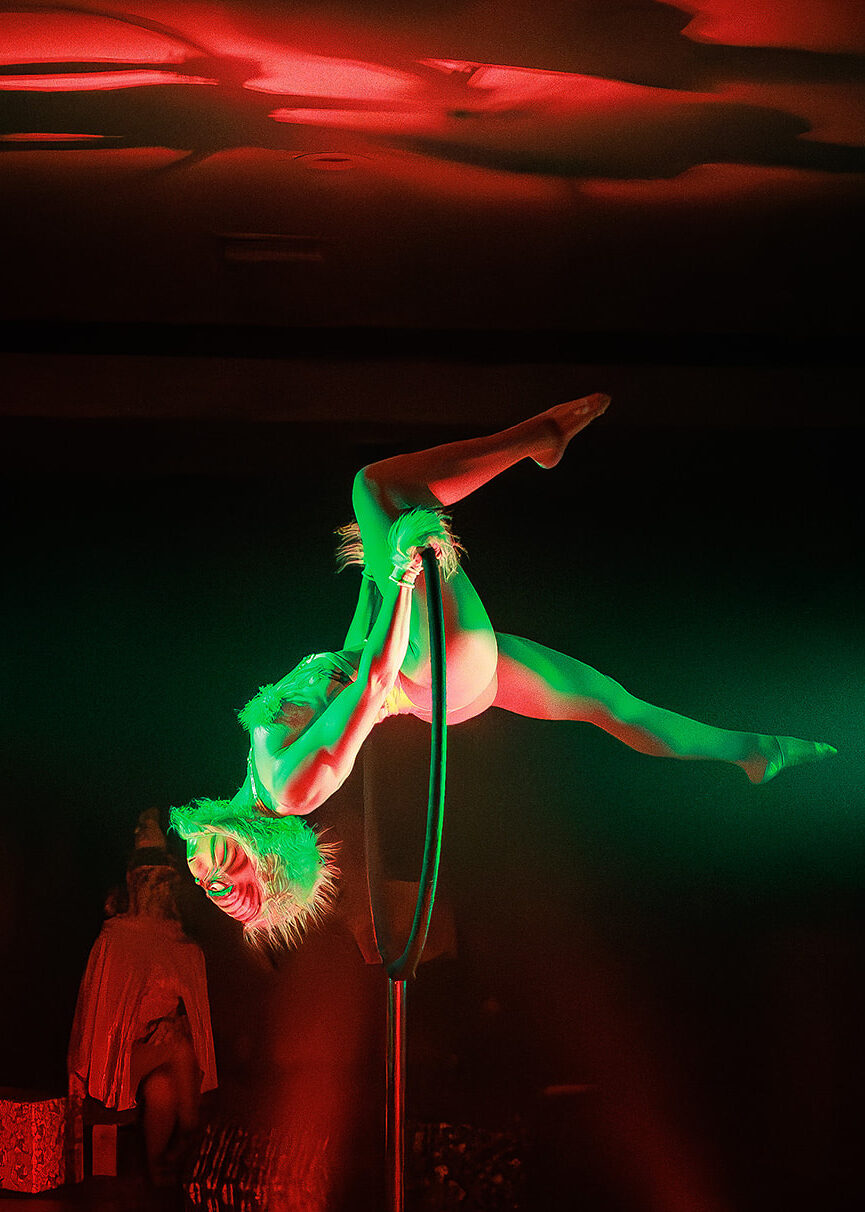 picture of a woman performing burlesque in a grinch mask 