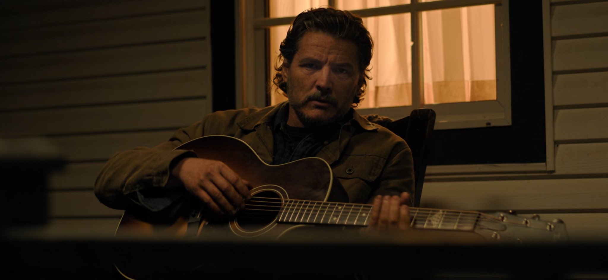 Joel sits on a porch and plays guitar