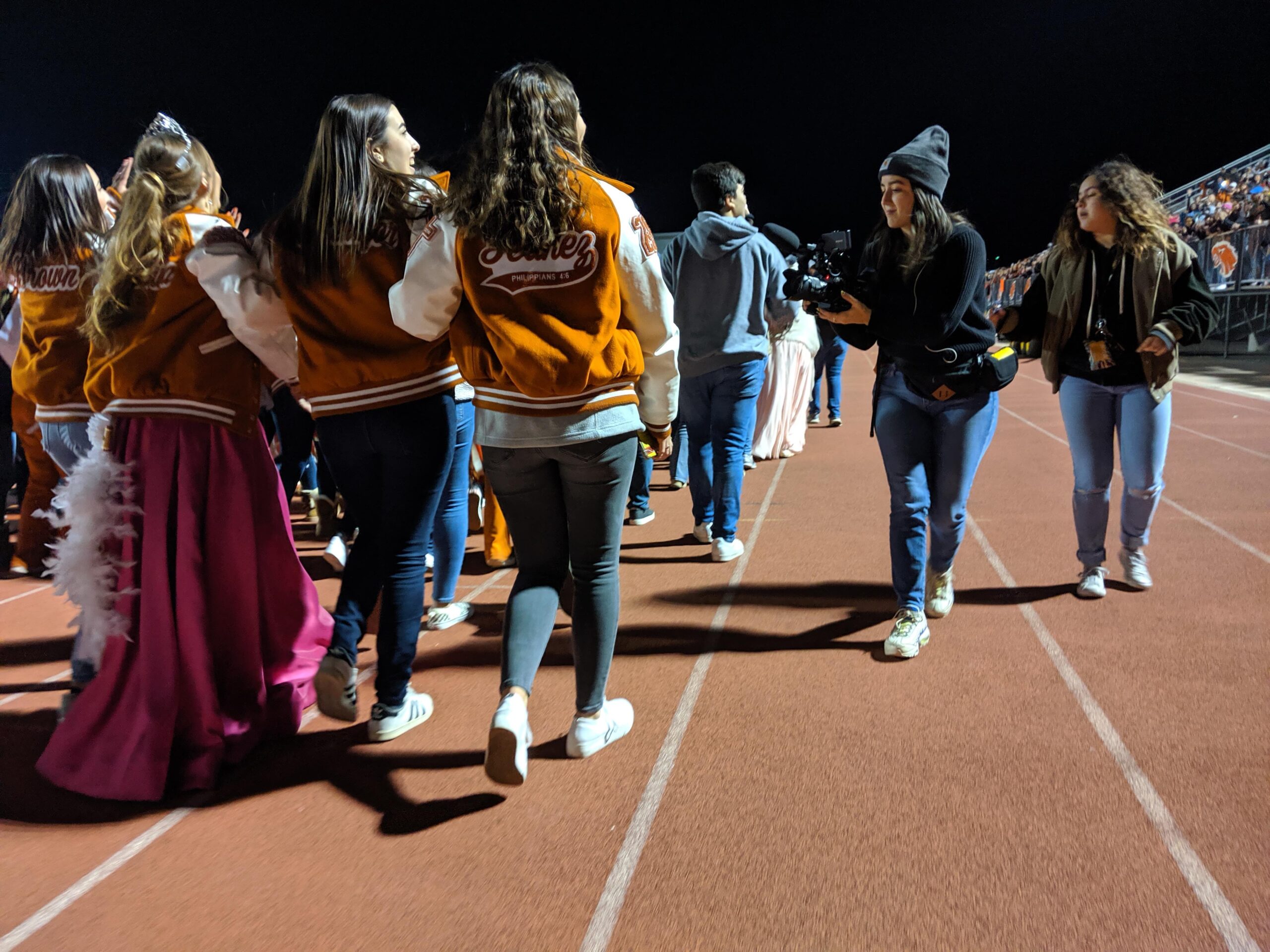 A group of high school seniors walk along a track as Robie Flores films.