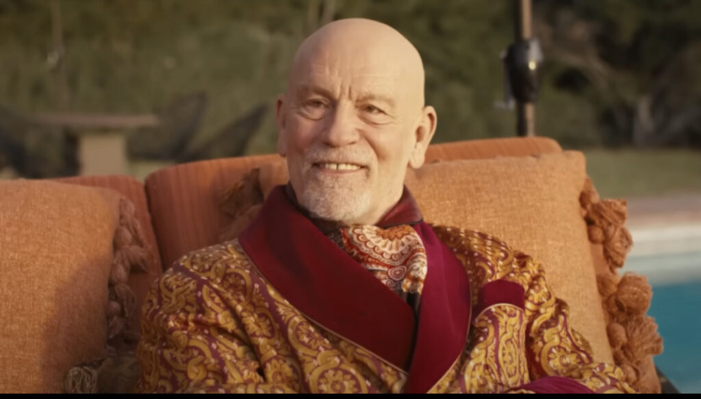 John Malkovich's Moretti lounges on a chair by a pool and smiles.