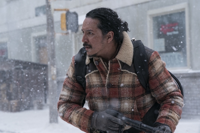 Tommy in the snowy streets of jackson, holding a rifle. Wearing a red plaid coat.