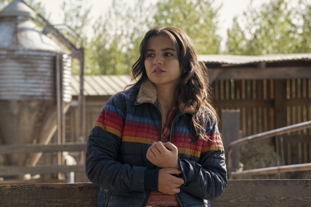 Dina wearing a blue, fur-lined jacket with rainbow stripes across the center.