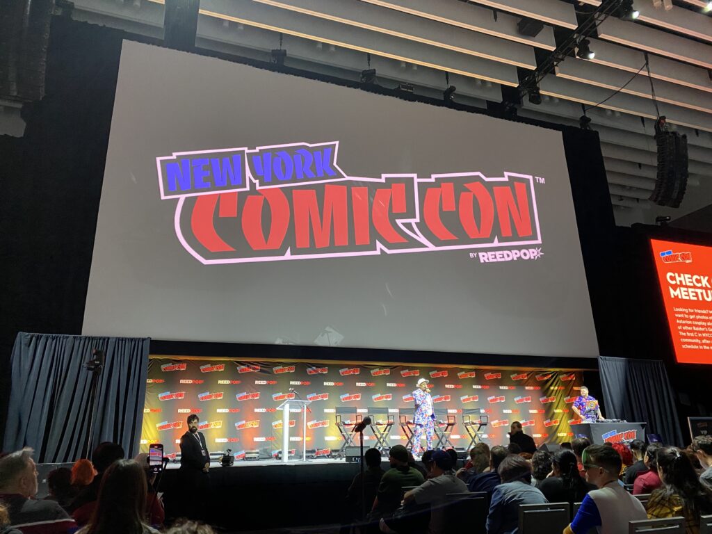 The Empire stage at NYCC 2024- one of the two large panel rooms at the Javits. A host and DJ are on stage getting ready to welcome the next panel.