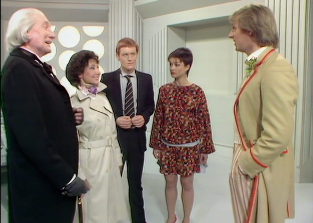 From left to right: The First Doctor (Richard Hurndall), Susan (Carole Ann Ford), Turlough (Mark Strickson), Tegan (Janet Fielding), and the Fifth Doctor (Peter Davison) stand in the Fifth Doctor's TARDIS console room