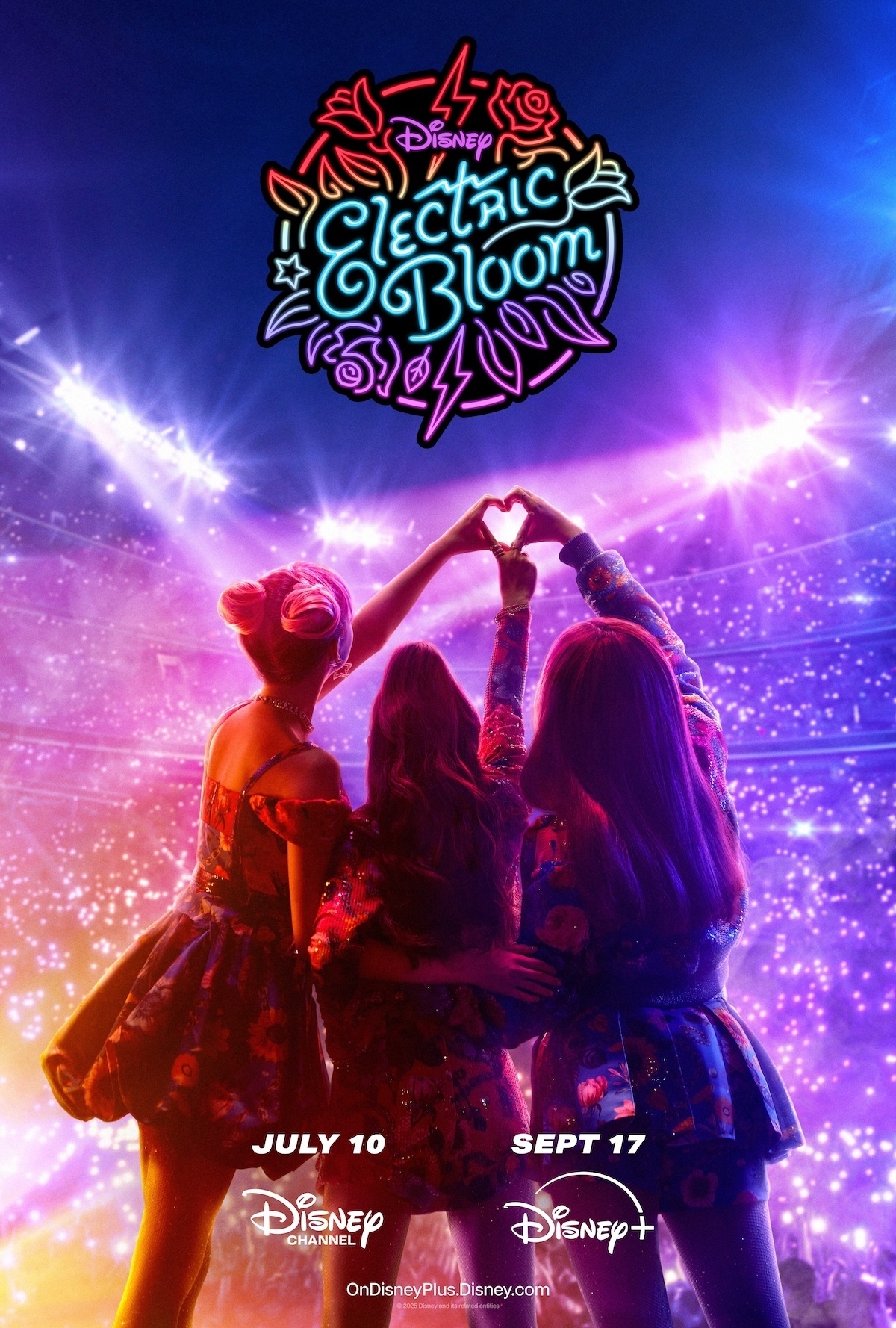 Tulip, Posey and Jade the band members in Electric Bloom pose on stage with their hands making the shape of a heart.