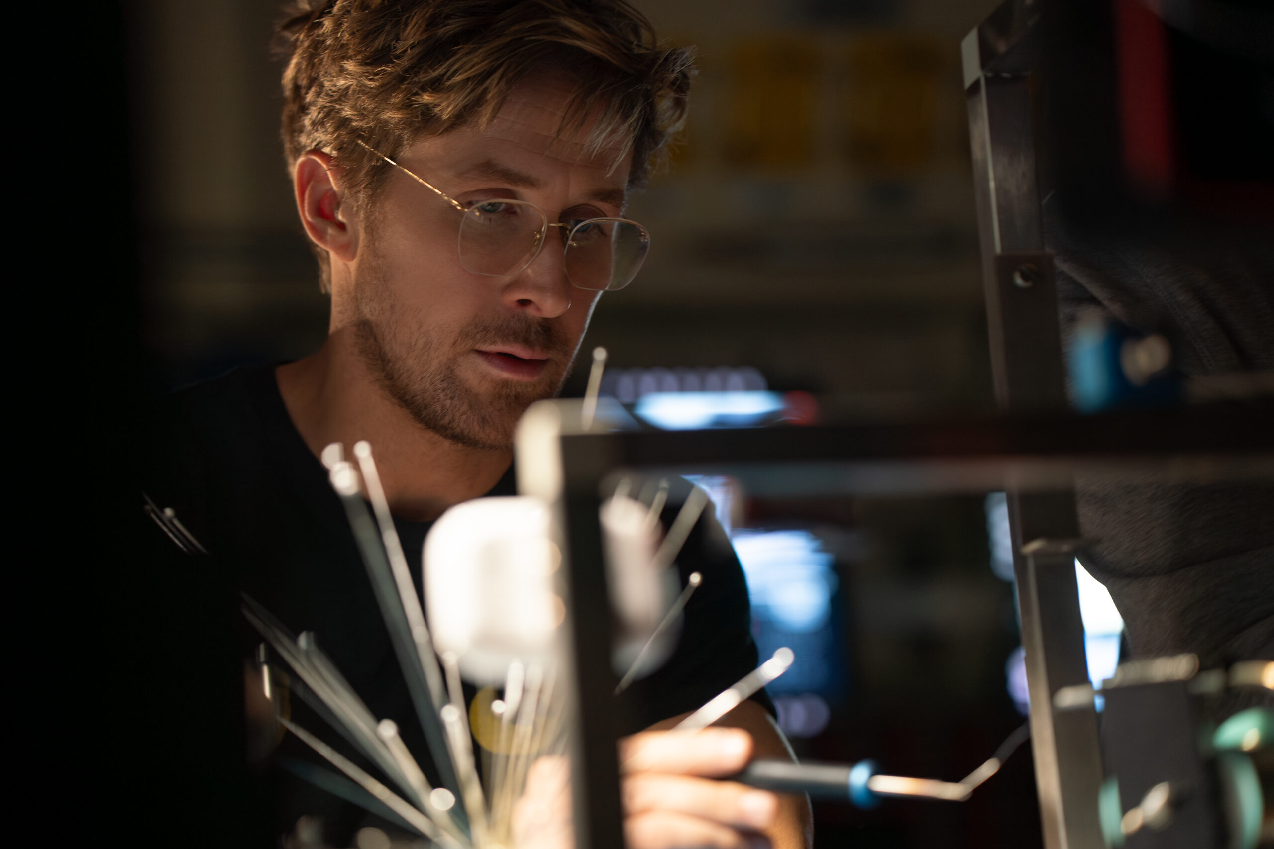 Ryan Gosling as Andy Weir in Project Hail Mary looking at a Desk